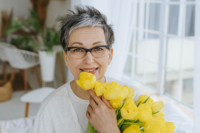 Smiling woman with bunch of tulips at home