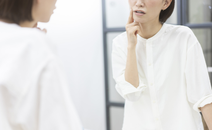 Japanese woman in front of a mirror worrying about her skin (People)