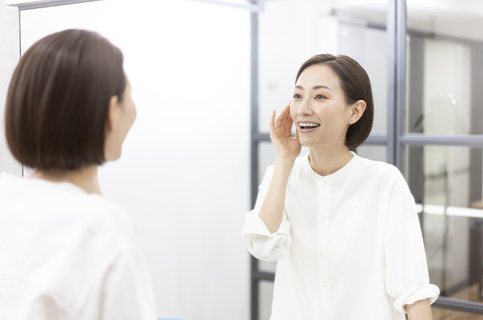 Japanese woman checking her smile in the mirror (People)