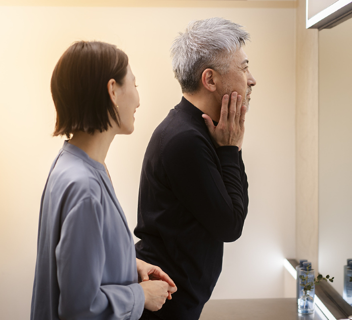Japanese man learning skin care from his wife at night (People)