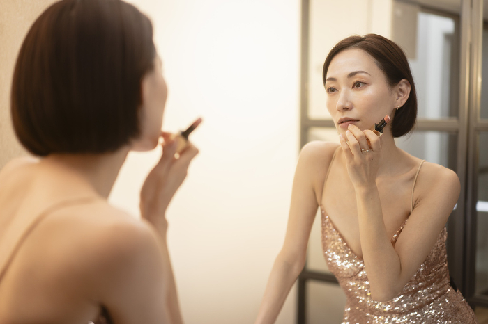 Japanese woman applying makeup in front of a mirror (People)