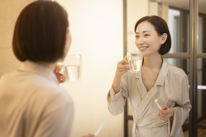 Japanese woman brushing her teeth in front of a mirror (People)
