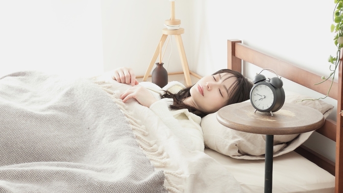 Japanese woman sleeping with alarm clock set (People)