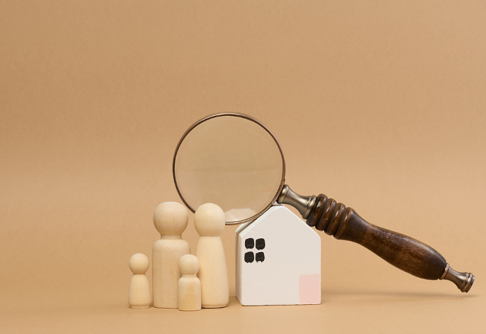 Magnifying glass and a family of wooden figures on the backgroun Magnifying glass and a family of wooden figures on the background of a house, the concept of searching for real estate rental, mortgage
