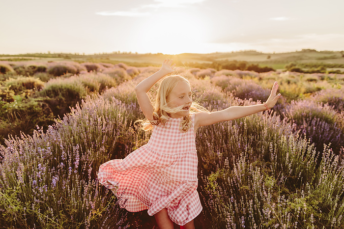 Carefree girl dancing amidst flowers in lavender field on sunset Carefree girl dancing amidst flowers in lavender field on sunset