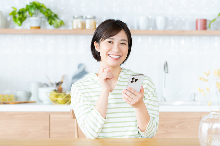 Young Japanese woman looking at her phone in the kitchen/dining room (People)