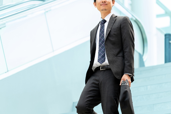 Japanese male businessman walking in an office district (People)