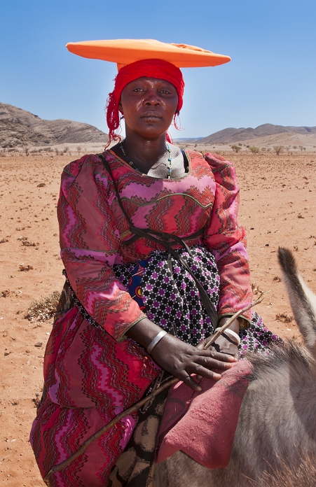 Africa Namibia Namibia Africa Northern Desert Herero woman with hat riding mule herding goats in Tomakas in Puros Conservancy remote farming