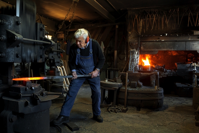 Germany, Bavaria, Josefsthal, senior  blacksmith at work in historic blacksmith's shop