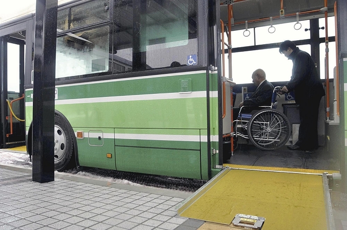 Nonstop bus 1 Akita Chuo Kotsu employees trying out a wheelchair ramp and actually pushing a wheelchair  in front of JR Tsuchizaki Station on March 25 .