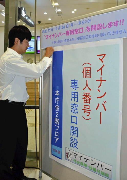 national identification number system A staff member displays a poster announcing the opening of a dedicated My Number counter at the entrance of City Hall in Kofu City on March 23.