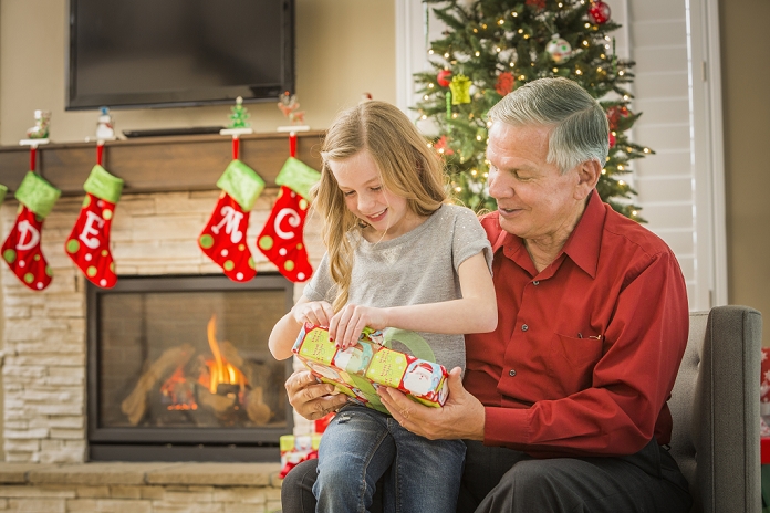 Grandfather and grandchildren spending Christmas Caucasian grandfather opening Christmas gifts with granddaughter