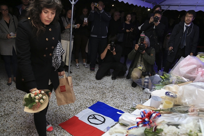 Paris Terrorist Attacks. Mourning the Victims in Tokyo A woman places flowers in a gesture of condolence and solidarity for the victims of the terrorist attacks in Paris on last Friday at the Embassy of France in Tokyo, Japan on November 15, 2015. In a gesture of condolence and solidarity with the French people the Chief Cabinet Secretary Yoshihide Suga, Tokyo Governor Yoichi Masuzoe and local Japanese and French attended a special ceremony at the Embassy of France in Tokyo. After the event a small group met outside Shibuya station to sing the Marseillaise. Tokyo also paid respect by illuminating Tokyo Tower and Tokyo Skytree in blue, white and red, the colors of the French flag.  Photo by Rodrigo Reyes Marin AFLO 