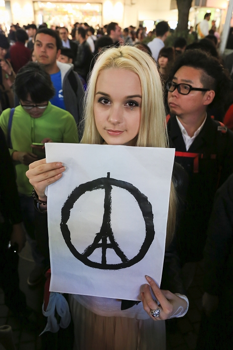 Paris attacks. Tokyo Mourns the Victims A woman shows the Eiffel Tower as a symbol of peace to pay respect for the victims of the terrorist attacks in Paris on last Friday, near to the Shibuya scramble crossing in Tokyo, Japan on November 15, 2015. In a gesture of condolence and solidarity with the French people the Chief Cabinet Secretary Yoshihide Suga, Tokyo Governor Yoichi Masuzoe and local Japanese and French attended a special ceremony at the Embassy of France in Tokyo. After the event a small group met outside Shibuya station to sing the Marseillaise. Tokyo also paid respect by illuminating Tokyo Tower and Tokyo Skytree in blue, white and red, the colors of the French flag.  Photo by Rodrigo Reyes Marin AFLO 