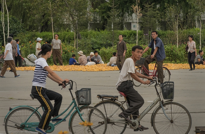 Hamhung, North Korea People and passersby drying corn on a street near Hamhung Station, September 3, 2012.