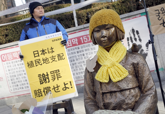 Japan South Korea Agreement on Comfort Women Issue Protest Demonstration at Comfort Women Statue Peace Monument, Dec 29, 2015 : The Peace Monument symbolizing Korean Comfort Women or sex slaves during the Second World War, is seen in front of the Japanese Embassy in Seoul, South Korea as a protester holds a sign. Local media reported that Japanese Prime Minister Shinzo Abe apologized to the Korean victims of Japan s wartime sexual slavery, Japan provided a 1 billion yen  US 8.3 million  fund for the victims and South Korea will refrain from blaming Japan over the issue, under the deal announced on Monday between the two countries. South Korean critics say questions remain if Tokyo legally admitted its  responsibilities  over its wartime atrocities, according to local media. South Korea agreed to work on Japan s demand that the Peace Monument be removed from outside the Japanese Embassy in Seoul.  Photo by Lee Jae Won AFLO   SOUTH KOREA 