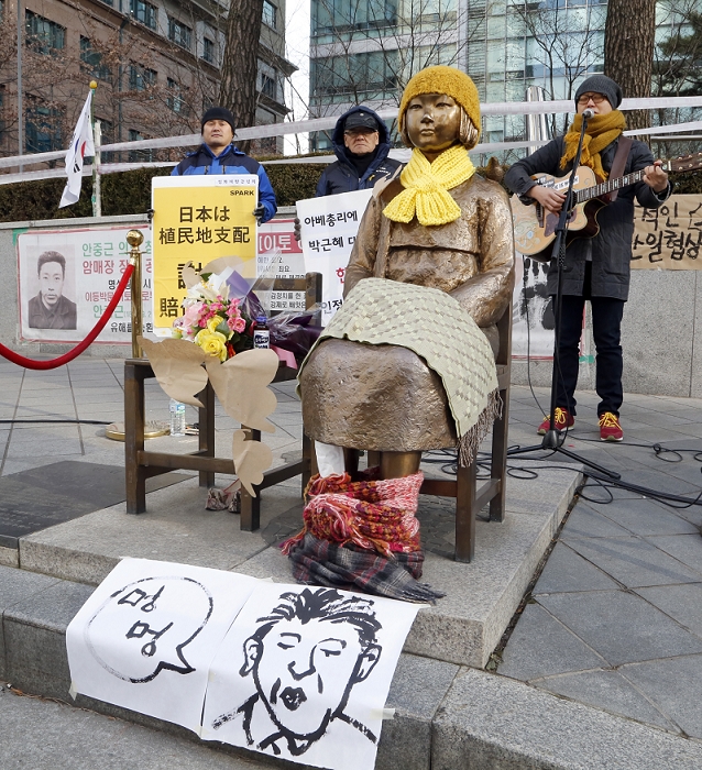 Japan South Korea Agreement on Comfort Women Issue Protest Demonstration at Comfort Women Statue Peace Monument, Dec 29, 2015 : A portrait resembling Japanese Prime Minister Shinzo Abe, which South Korean painter Shin Hye Won drew, is seen under the Peace Monument symbolizing Korean Comfort Women or sex slaves during the Second World War, in front of the Japanese Embassy in Seoul, South Korea as South Korean singer esSsin  R  sings a song during a protest against which he calls,  shameful deal  over comfort women between South Korea and Japan. Local media reported that Japanese Prime Minister Abe apologized to the Korean victims of Japan s wartime sexual slavery, Japan provided a 1 billion yen  US 8.3 million  fund for the victims and South Korea will refrain from blaming Japan over the issue, under the deal announced on Monday between the two countries. South Korean critics say questions remain if Tokyo legally admitted its  responsibilities  over its wartime atrocities, according to local media. South Korea agreed to work on Japan s demand that the Peace Monument be removed from outside the Japanese Embassy in Seoul.  Photo by Lee Jae Won AFLO   SOUTH KOREA 