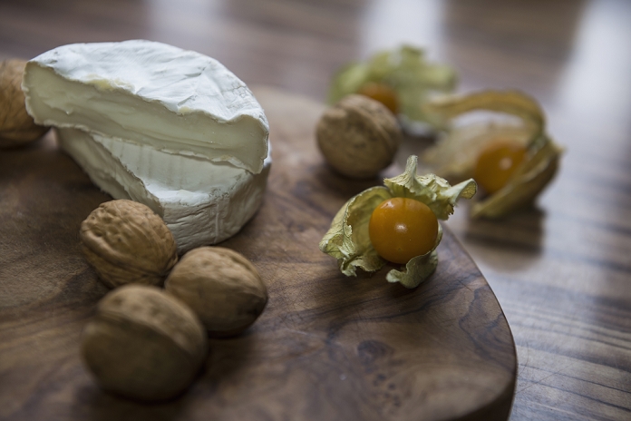 Close up of two halves of cheese and walnuts with a Cape Gooseberry, Germany