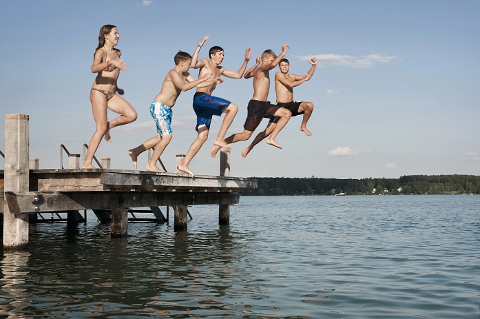 Five teenagers jumping from a jetty into lake