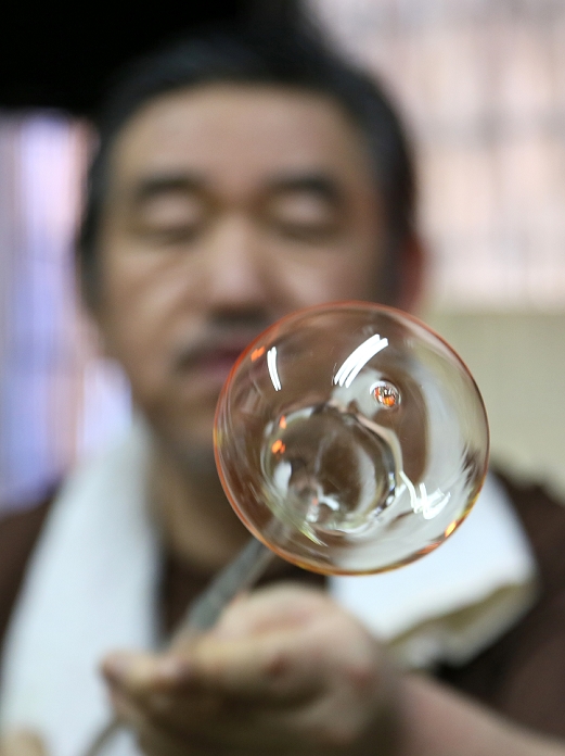 Japanese Occupation Edo Fu ring  March 31, 2016  March 31, 2016, Tokyo, Japan   Masayoshi Shinohara checks the finish of a wind bell he has just blown from a blob of molten glass at his workshop in downtown Tokyo on Thursday, March 31, 2016. Traditional Japanese wind chimes have captured the hearts of Japanese with their beautiful sounds since the 18th century when Dutch glass making techniques were first introduced to Japan. One of the characteristics of the authentic Japanese glass wind bells is that the painting is done from inside in order to keep the colors from fading.  Photo by Haruyoshi Yamaguchi AFLO  VTY  mis 