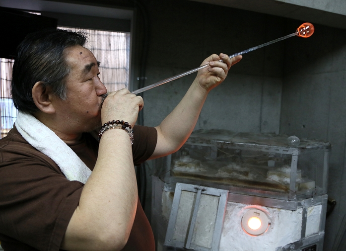 Japanese Occupation Edo Fu ring  March 31, 2016  March 31, 2016, Tokyo, Japan   Masayoshi Shinohara blows a blob of molten glass into the shape of a wind bell at his workshop in downtown Tokyo on Thursday, March 31, 2016. Traditional Japanese wind chimes have captured the hearts of Japanese with their beautiful sounds since the 18th century when Dutch glass making techniques were first introduced to Japan. One of the characteristics of the authentic Japanese glass wind bells is that the painting is done from inside in order to keep the colors from fading.  Photo by Haruyoshi Yamaguchi AFLO  VTY  mis 