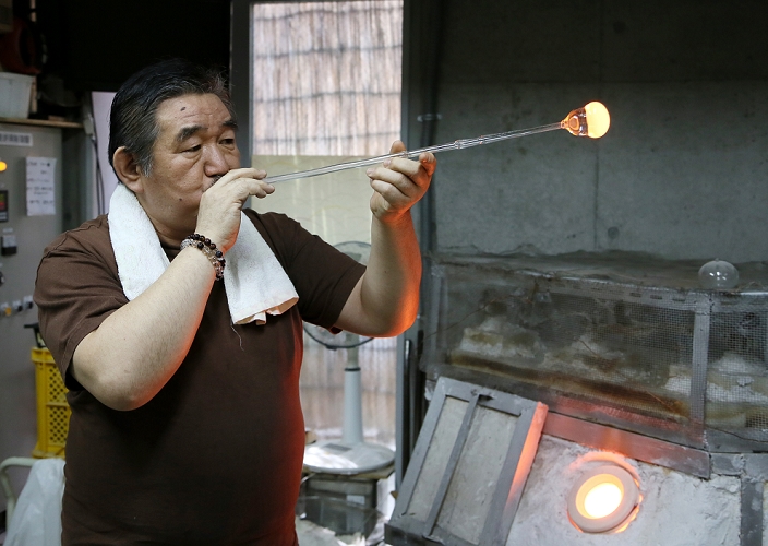 Japanese Occupation Edo Fu ring  March 31, 2016  March 31, 2016, Tokyo, Japan   Masayoshi Shinohara blows a blob of molten glass into the shape of a wind bell at his workshop in downtown Tokyo on Thursday, March 31, 2016. Traditional Japanese wind chimes have captured the hearts of Japanese with their beautiful sounds since the 18th century when Dutch glass making techniques were first introduced to Japan. One of the characteristics of the authentic Japanese glass wind bells is that the painting is done from inside in order to keep the colors from fading.  Photo by Haruyoshi Yamaguchi AFLO  VTY  mis 