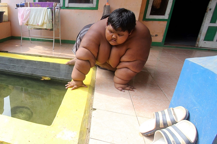 Arya boy from Indonesia 10 years old, weighs 192 kg. KARAWANG, INDONESIA   JUNE 14 : Arya Permana  10 years  swim on the pool made specifically in his yard for every three hours he s feeling the heat on June 13, 2016 in Karawang, West Java Province, Indonesia. Arya Permana is son of Ade Somantri and Rokayah is a giant boy in Indonesia with 192 Kg of body weight. According to his father, Ade Somantri, Arya normal birth weight of about 4 kilograms. Food consumed Aria normal at birth as well as consumed his brother. Currently under five years old, Arya had trouble defecate, and then taken to the doctor. Doctors then provide medicines and vitamins because Arya difficul to eat. Since Aria was 8 years old, from physical changes. His body continued to be heavy, whereas activity and eat like other kids.Photo by Rimba Putra Aditya Sijori Images