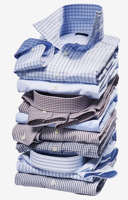 Stack of multi coloured checked and striped shirts on white background, studio shot
