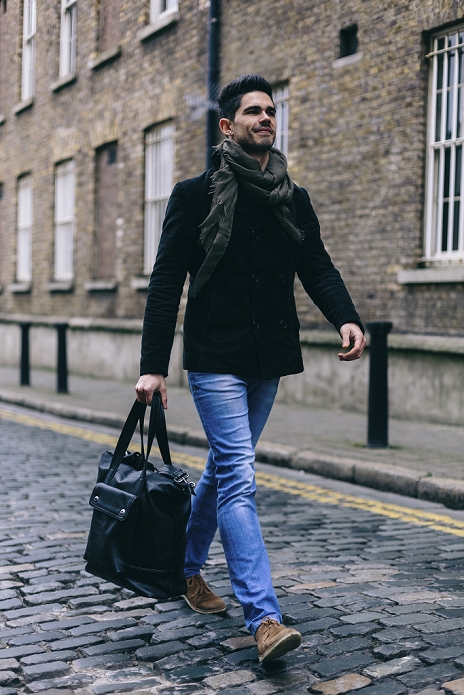 Young casual businessman walking in the street, carrying bag