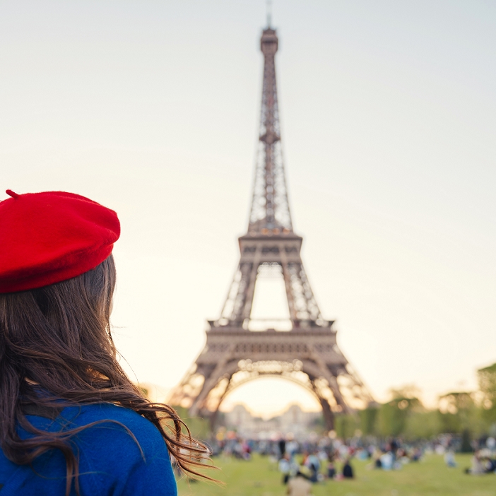 France, Paris, Champ de Mars, back view of woman wearing red beret looking at Eiffel Tower