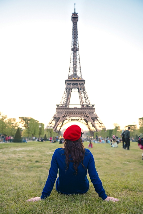 France, Paris, Champ de Mars, back view of woman sitting on meadow  looking at Eiffel Tower