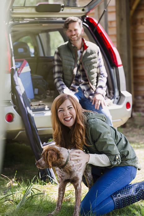 Portrait enthusiastic woman with dog outside car