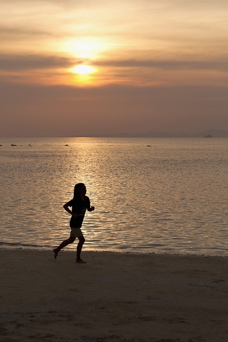 Woman running on a beach at sunset, Hat Tham Phra Nang beach, Krabi, Thailand, Asia