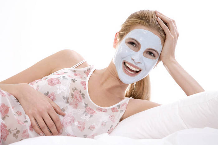 MAEF00251 Woman with beauty mask on face, lying on bed, smiling