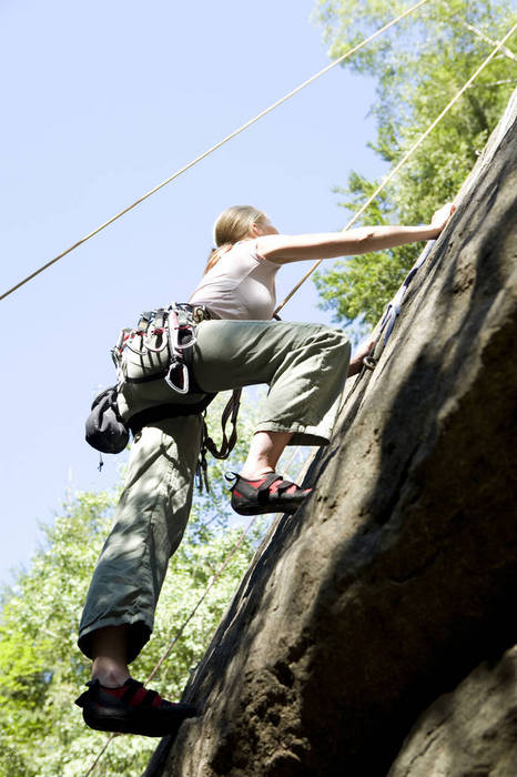 WESTF02341 Young woman mountain climbing, low angle view