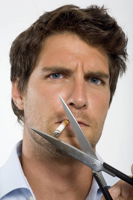 WESTF01630 Young man cutting cigarette with scissors, close up, portrait