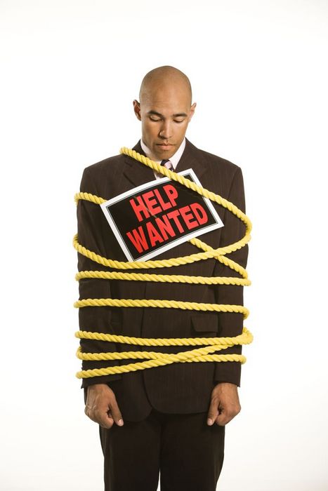 African American businessman wrapped in yellow rope wearing help wanted sign.