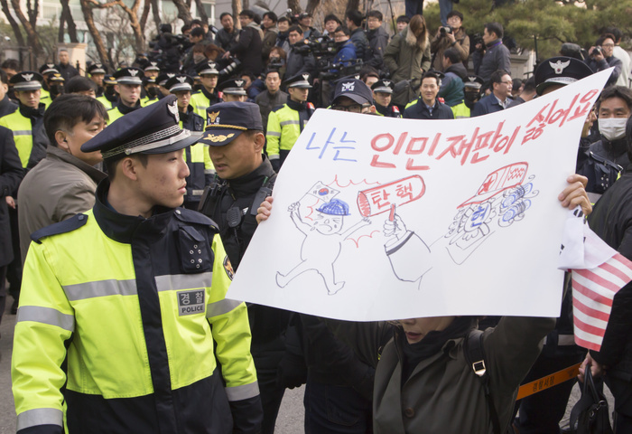 Police officers stand guard as a supporter of ousted president Park Geun Hye holds a sign in front of Park s home in Seoul South Korea Politics, Mar 21, 2017 : Police officers stand guard as a supporter of ousted president Park Geun Hye holds a sign in front of Park s home before she leaves to the Seoul Central District Prosecutors  Office to undergo prosecution questioning in Seoul, South Korea. The sign depicts South Korean Constitutional Court s ruling to oust Park Geun hye as  people s tribunal of communists . Park Geun hye became South Korea s first democratically elected president to be ousted and she has been named a criminal suspect for allegedly abusing her power and colluding with her longtime friend Choi Soon sil in extorting money from local conglomerates. The ex President Park was dismissed by the Constitutional Court on March 10, 2017 and faces a probe on 13 criminal allegations, local media reported.  Photo by Lee Jae Won AFLO   SOUTH KOREA 