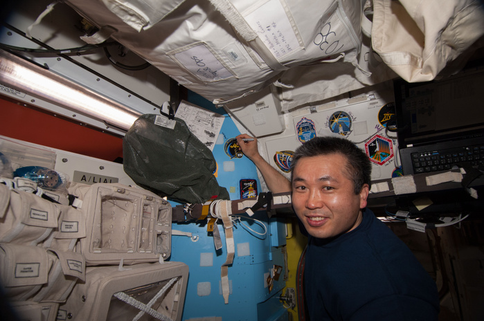 Captain Koichi Wakata, Expedition 39 Crew Member, International Space Station ISS039 E 020699  13 May 2014      Japan Aerospace Exploration Agency astronaut Koichi Wakata, Expedition 39 commander, places his crew patch on a wall in the Quest airlock of the Earth orbiting International Space Station. A short time later, Wakata joined Expedition 39 Soyuz Commander Mikhail Tyurin of Roscosmos and Flight Engineer Rick Mastracchio of NASA as they departed the orbital outpost in a Soyuz vehicle. Wakata had spent a great deal of time in Quest as he assisted spacewalks from the shirt sleeve environment of the orbital outpost on both Expedition 38 and 39.