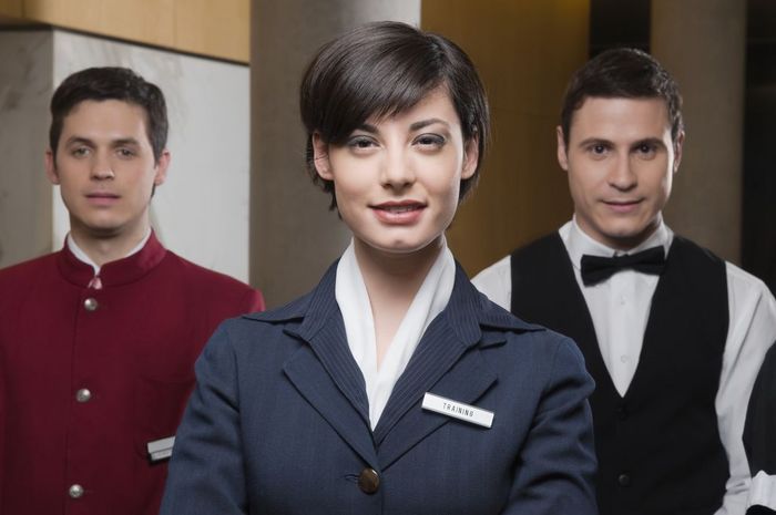Portrait of a receptionist standing with two waiters