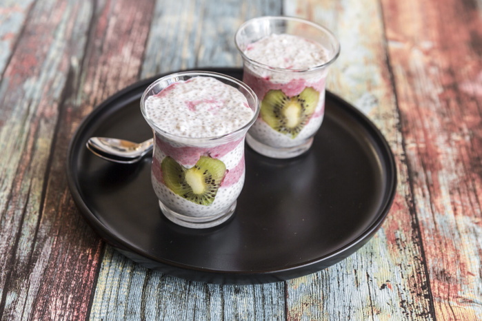 Two glasses of chia pudding with heart-shaped kiwi slices on tray