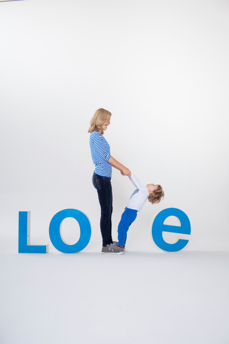 parent and child Mother and son holding hands, standing between three dimensional letters, creating the word LOVE