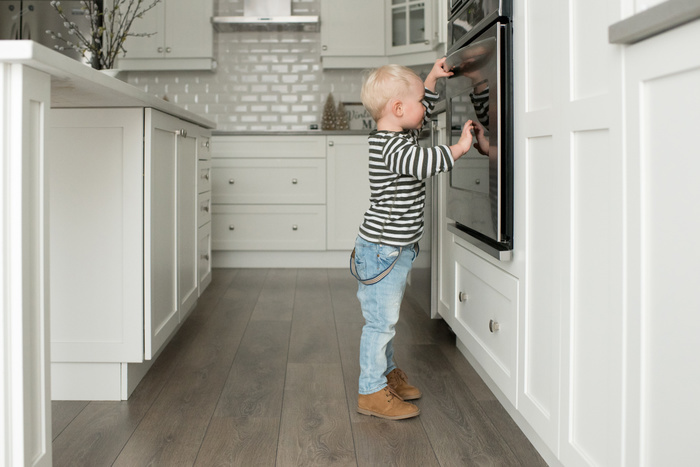   Young boy in kitchen, looking in oven