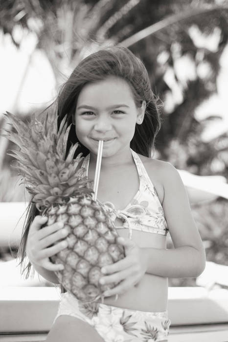 Little girl drinking from pineapple (Sepia photograph).