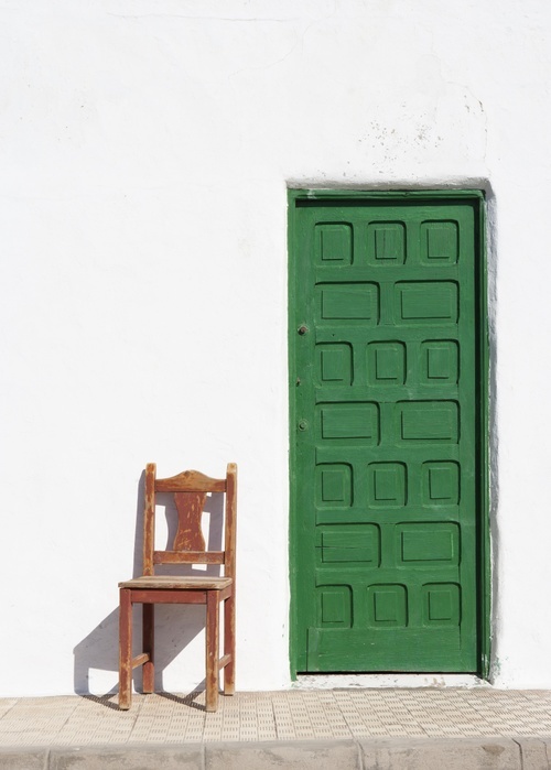   Green door with wooden chair in front of white house wall, El Puerto de la Cruz, Peninsula Jandia, Fuerteventura, Canary Islands, Spain, Europe