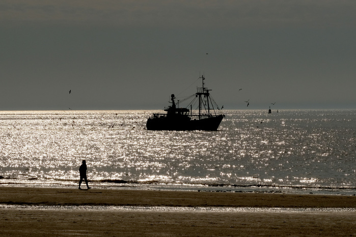 Summer in the Netherlands Sgeffeningenigen A person walks along a shore as a fishing boat moves on the ocean at Scheveningen, Holland s most popular beach resort, in Den Haag, the Netherlands, May 23, 2017.  Photo by Yuriko Nakao AFLO 