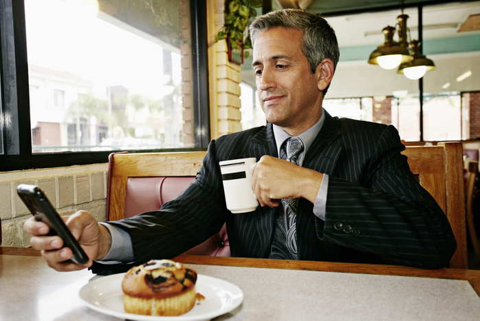 Businessman operating a smartphone Hispanic businessman using cell phone in restaurant