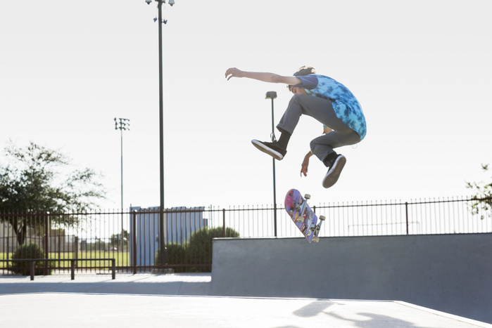 Skateboarding youth Hispanic man performing mid air trick on skateboard