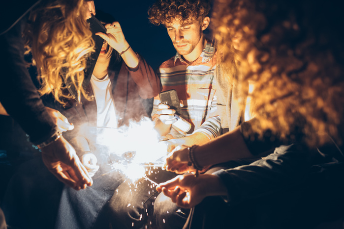 Group of friends enjoying roof party, lighting sparklers
