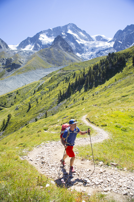 A hiker is ascending a curly trail above Arolla in the Swiss Alps. A hiker is ascending a curly trail above Arolla in the Swiss Alps. It is half way the Haute Route, a classic multi day hike between Chamonix in France and Zermatt in Switzerland. 